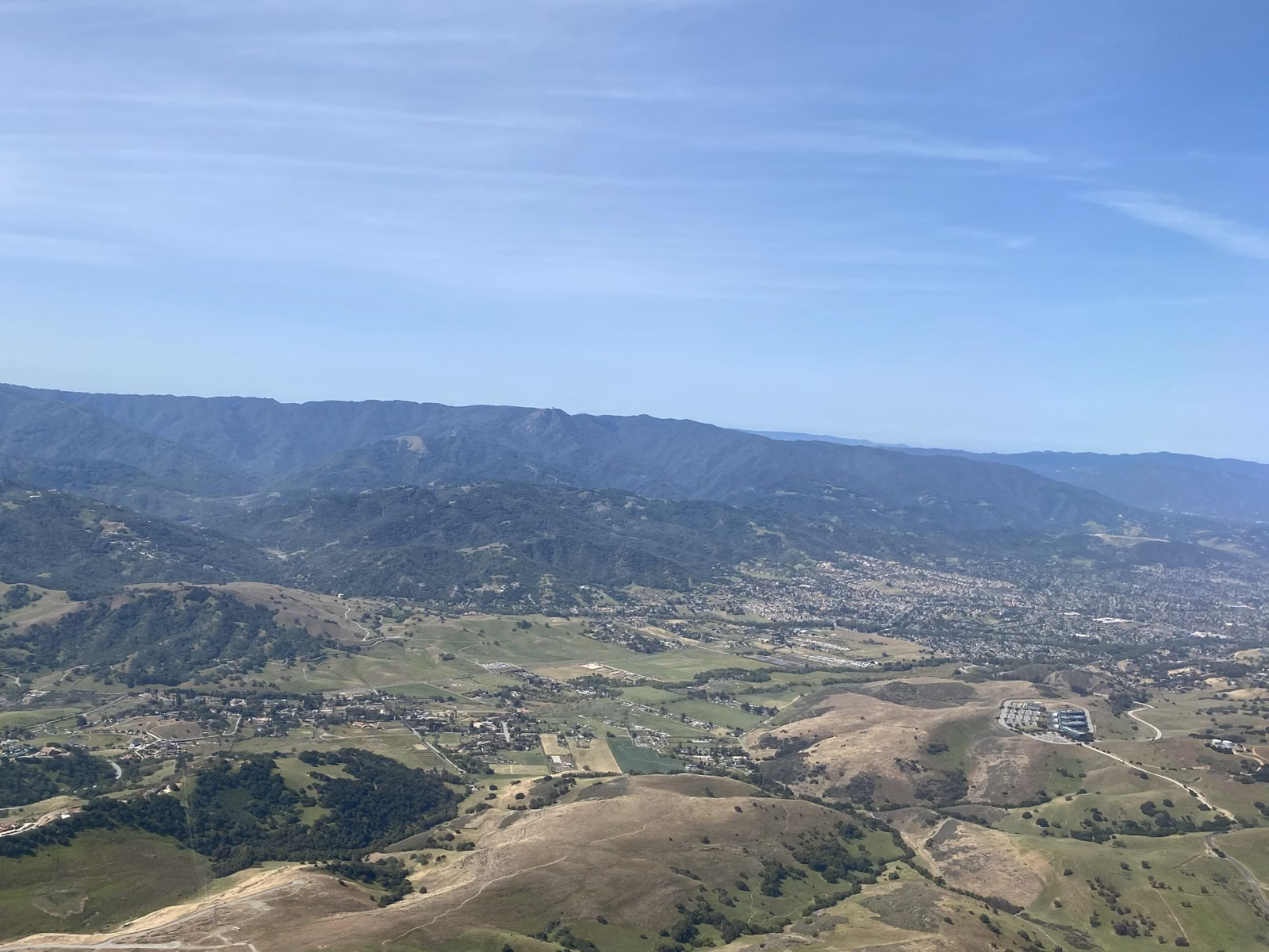 Aerial view of the forested ridges and valleys of the Santa Cruz Mountains under a clear sky