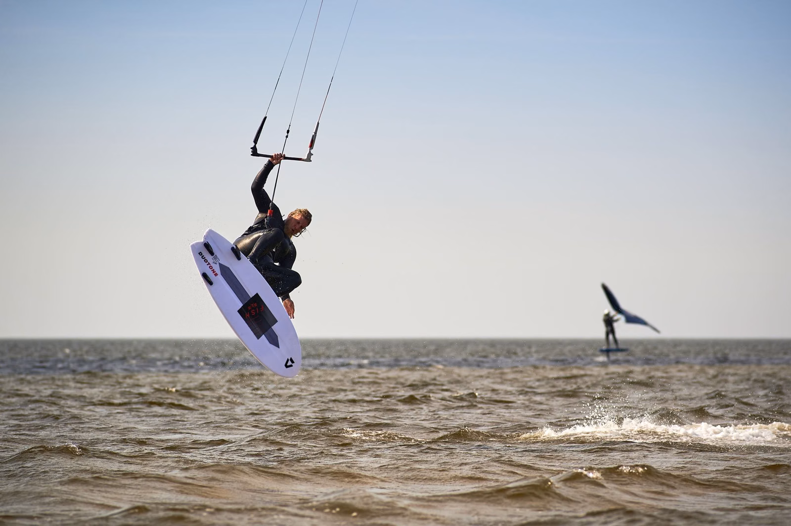 A kiteboarder airborne above choppy ocean water
